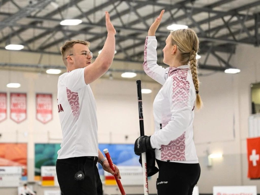 Latvijas izlases kērlinga spēlētāji sacensībās, ģērbušies vienādās sporta formās ar personalizētu apdruku.