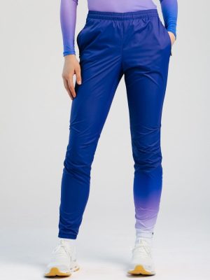 A studio shot of professional custom teamwear training pants for women, featuring a vibrant blue-to-purple sublimation gradient on the lower leg and an elastic waistband, designed for high-performance comfort and durability.