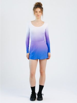 A model poses in custom team dancewear featuring an overlapping A-line skort with integrated shorts, paired with a matching long-sleeve purple-to-blue gradient dance body.