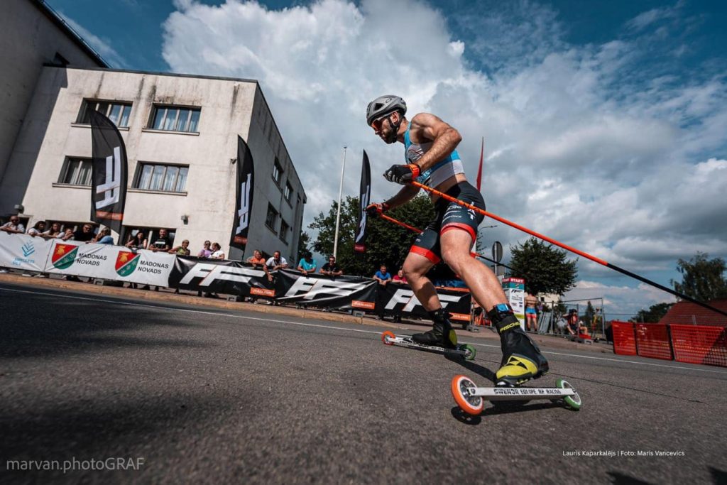 Male athlete competing in a rollerski race wearing custom team sportswear.