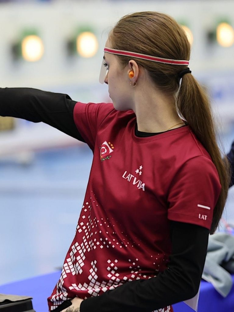 Female athlete in professional custom sublimation sportswear Latvia national team shirt during a shooting competition.