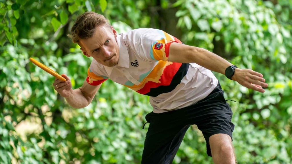 A disc golf player prepares a throw wearing a custom Chilli Disc Golf, illustrating professional sublimation-printed sportswear for outdoor sports.