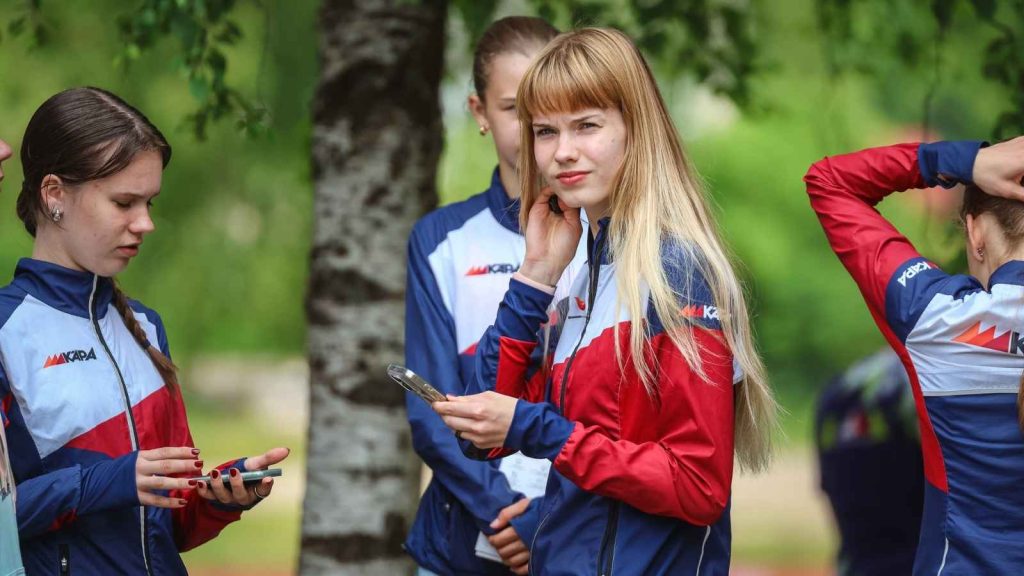 A group of athletes stands together in matching Kapa team custom branding training jackets, featuring a professional tri-color design in navy, red, and white.