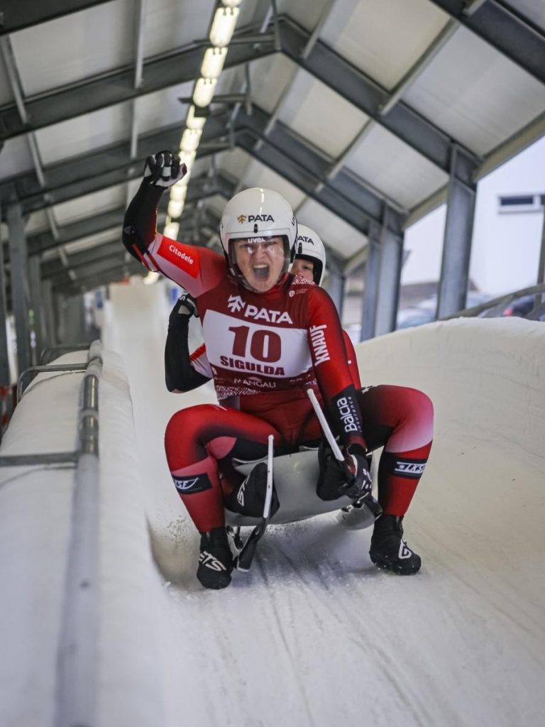 Two athletes racing down an ice track in a custom sportswear luge racing suit made with high quality sublimation print.