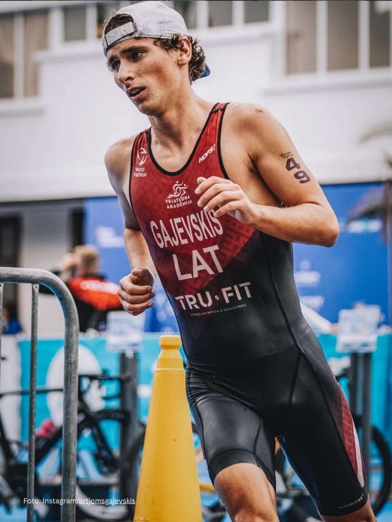 A triathlete racing on a course while wearing a custom sportswear trisuit produced with high quality sublimation print.