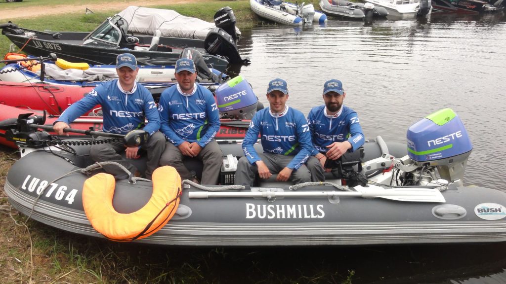 Custom fishing tournament team jerseys with sponsor logos and full sublimation print on a boat.