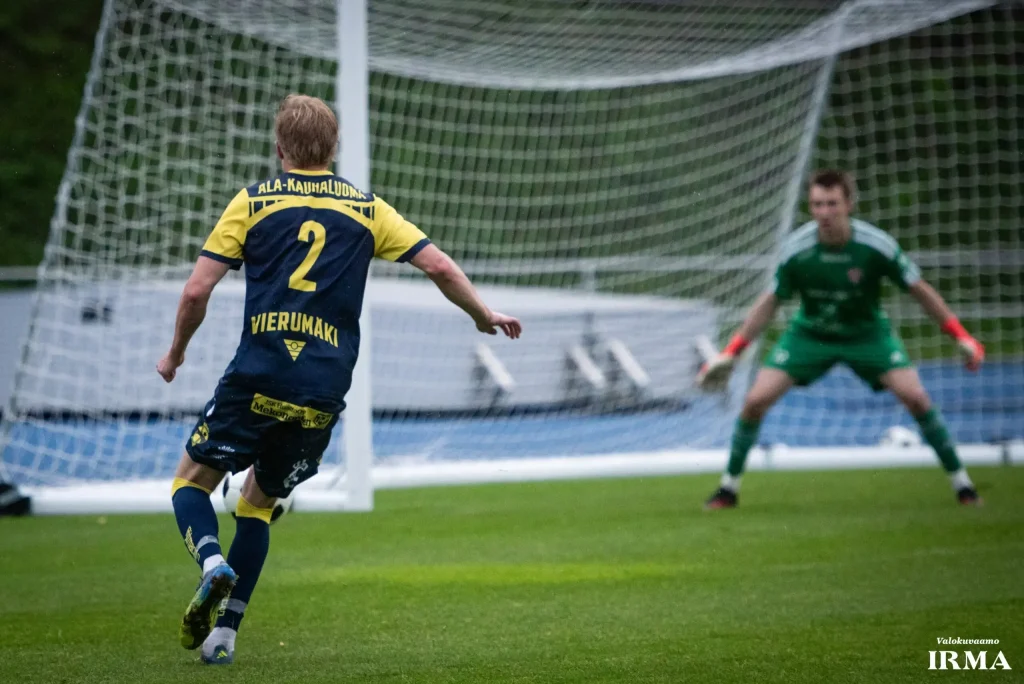 Union Plaani football player number 2, Ala-Kauhaluoma, taking a shot on goal against an opposing goalkeeper in green, photographed by Heikki Gröndahl for Valokuvaamo IRMA.